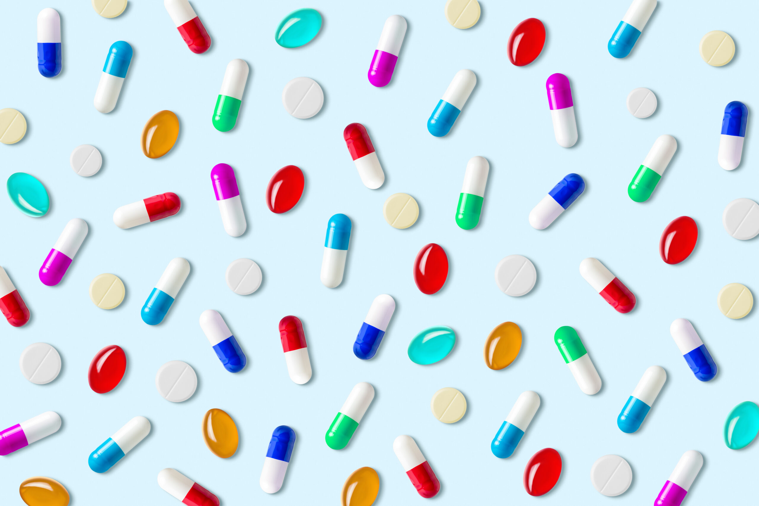 Creative layout of colorful pills and capsules on pastel blue background. Minimal pharmacy concept.