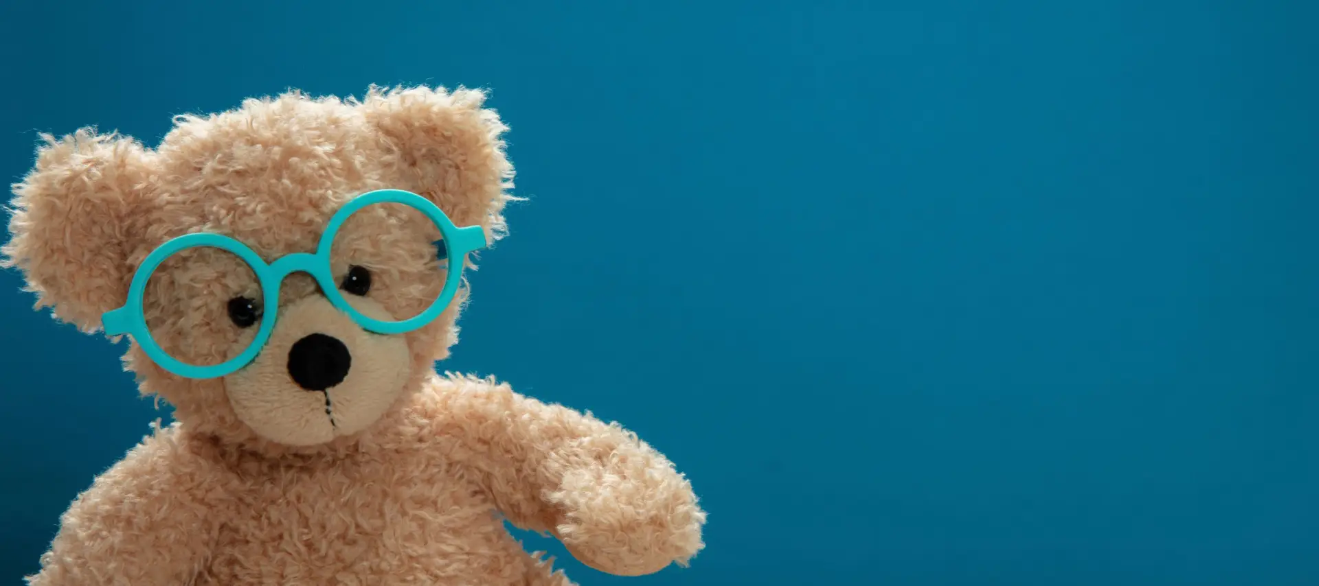 Cute teddy wearing glasses against blue background